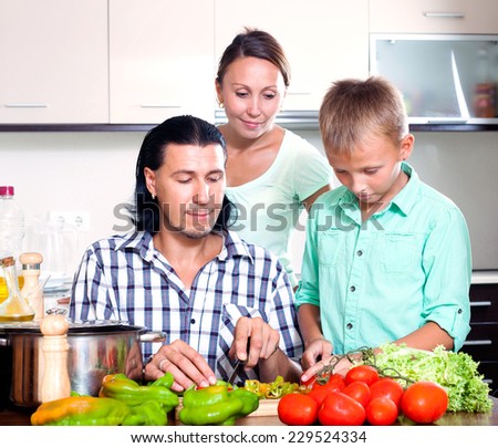 Happy family with teenager son cooking with fresh vegetables at home kitchen