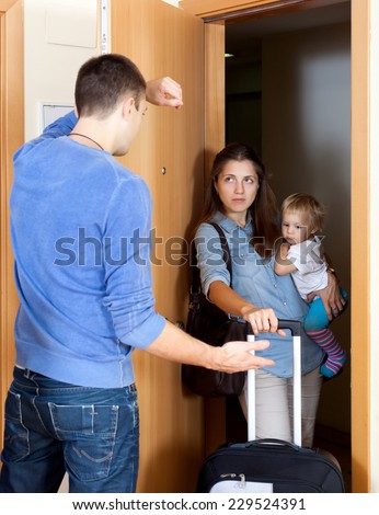 Family conflict. Sad man against wife with child in living room