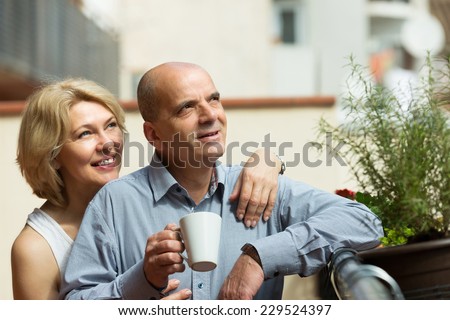 Smiling senior couple discussing and drinking coffee at balcony
