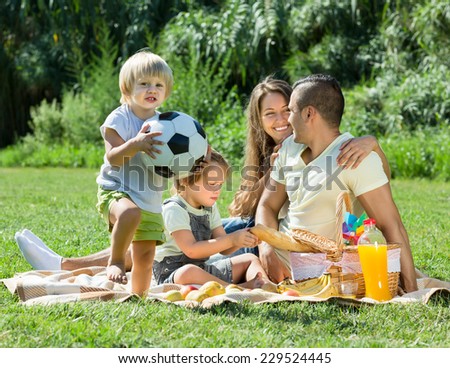 Young couple with little daughters having holiday with picnic. Focus on girl