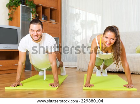 Young smiling people doing yoga on mats in room