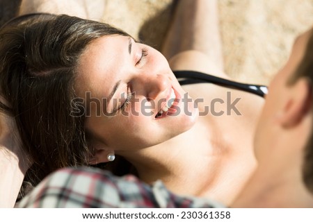 Smiling young woman lying on the lap of a young man