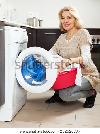 Home laundry. Happy Housewife using washing machine at home