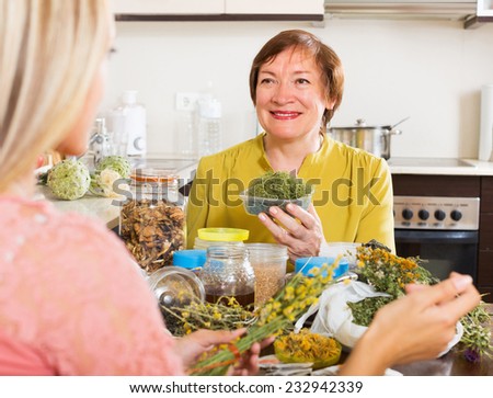 Smiling mature woman with daughter with dried herbs