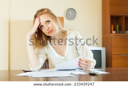 Sad long-haired woman reading document at home