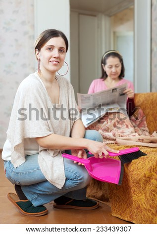 Clean up woman, while her mature mother lying on the sofa at home