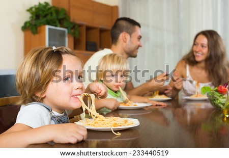 happy family of four  having lunch with pasta at home together. Focus on first baby