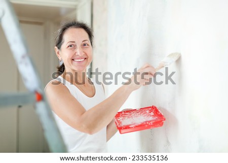 Happy mature woman makes repairs at home