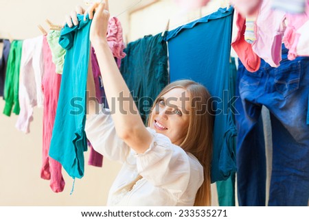 Positive long-haired housewife drying clothes on clothes-line