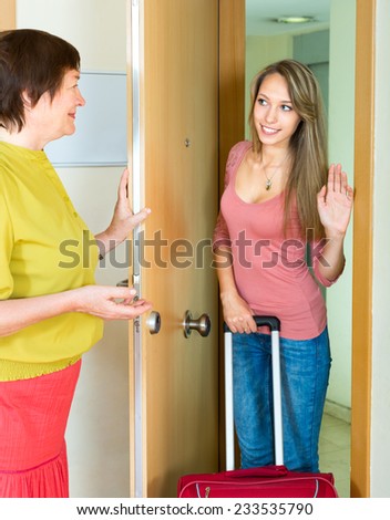 Senior mother seeing traveling daughter with baggage to the door