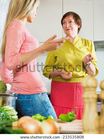 Sad mature woman with adult daughter  sharing bad news in kitchen