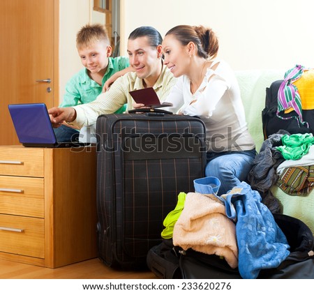 Three tourists packing luggage and reserving hotel over internet in home