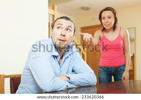 Family conflict. Serene guy listening to his angry woman at home