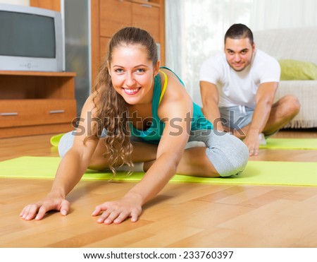 Young smiling people doing yoga on mats indoor