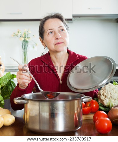 wife cooking soup with ladle in home kitchen