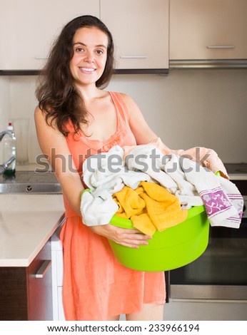 Home laundry. Smiling young housewife with linen basket near washing machine