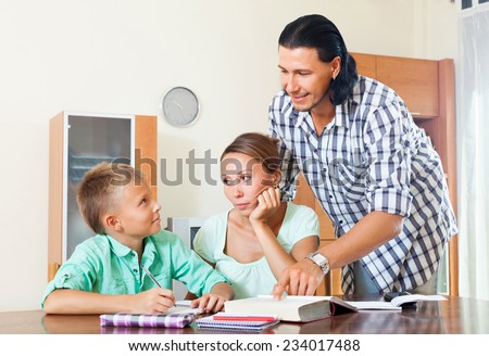 Smiling couple with teenager son doing homework in home interior