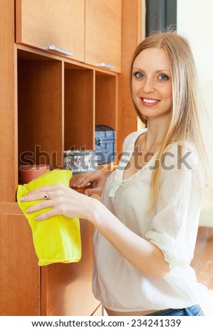 Blonde long-haired woman cleaning furniture at home