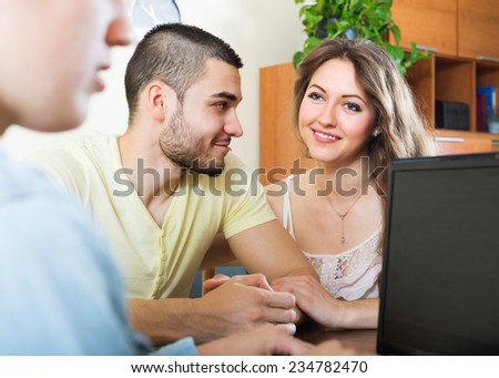 Happy couple talking with employee with laptop at home