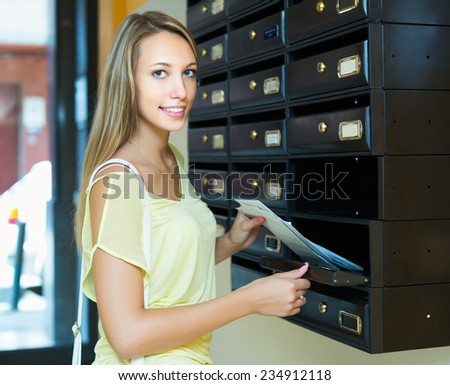 Smiling housewife checking up letter-box indoor