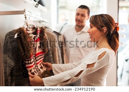 Ordinary couple choosing clothes at fashion boutique