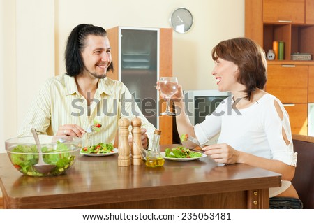 Gorgeous brunette woman with man eating veggie salad at home