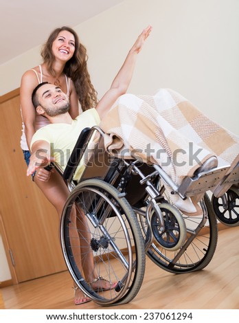 Happy friends with smiling  man on wheelchair in playful mood in home