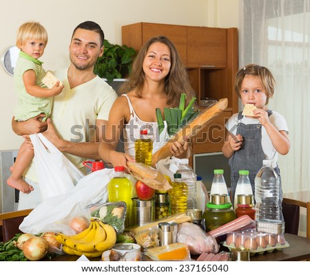 Cheerful family of four with bags of food in house