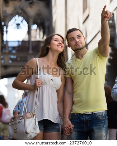 Smiling tourists couple walking through ancient European city