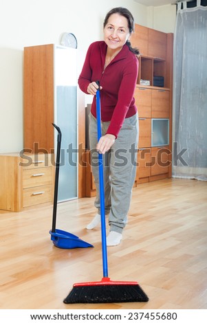 mature woman sweeping the floor at home