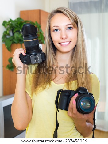 Young smiling girl testing  professional cameras