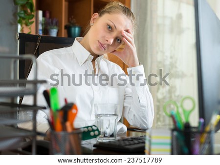 Portrait of exhausted young woman with headache at office