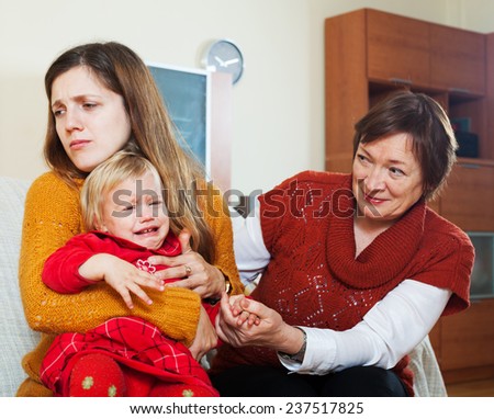 young sadness mother with crying baby and grandmother after quarrel at home