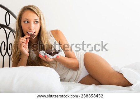 Beautiful girl eating chocolate in her bedroom