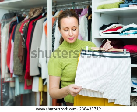 Long-haired woman choosing apparel on shelves at store
