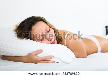 Middle-aged woman in underwear sleeping on white pillow at home