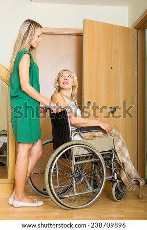 Happy woman in wheelchair with young assistant at threshold