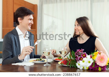 Young couple having romantic dinner with champagne and eating fish in home
