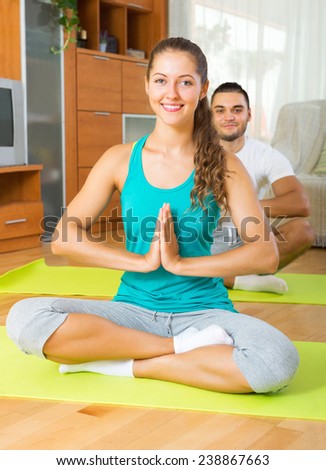 Adult smiling people doing yoga on mats in interior