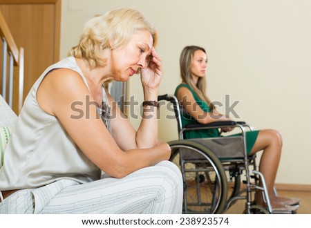 Upset elderly woman and handicapped female having domestic quarrel