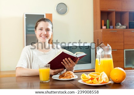 young woman with book during breakfast with juice in morning at home