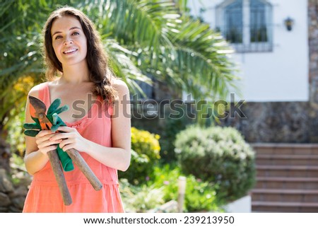 Happy woman with a secateurs in hands in the yard gardening