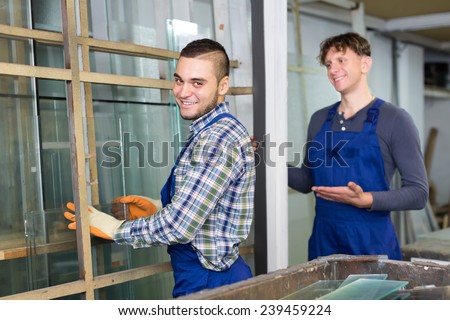 Two careful american workmen cutting glass for windows at workshop