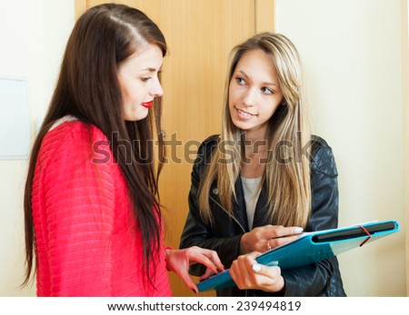 woman filling questionnaire for young employee with paper at door