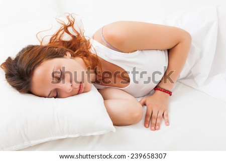 Beautiful red-haired girl quietly sleeping on a white pillow in bed at home