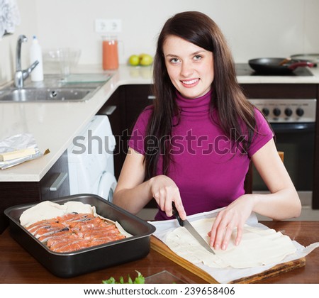 Smiling girl cooking fish pie with store-bought dough