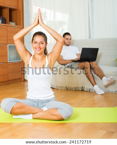 female in yoga position and lazy guy on sofa at home