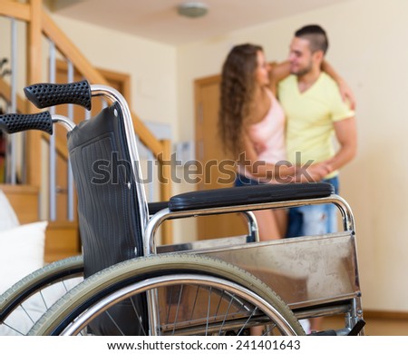Male social worker assisting girl during rehabilitational  period at home. Focus on wheelchair