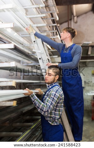 Young production workmen in uniform with different PVC window profiles