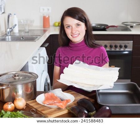 Smiling girl cooking fish pie with prepared store-bought dough at home kithen